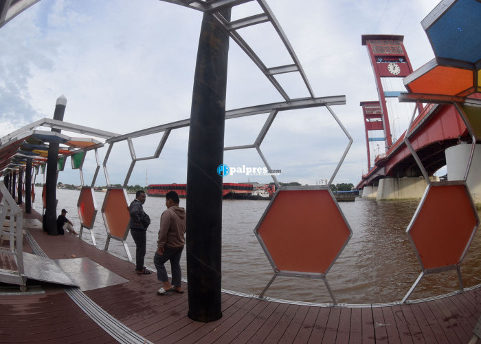Beberapa orang menikmati tepian sungai Musi dari Plaza Terminal Jukung.