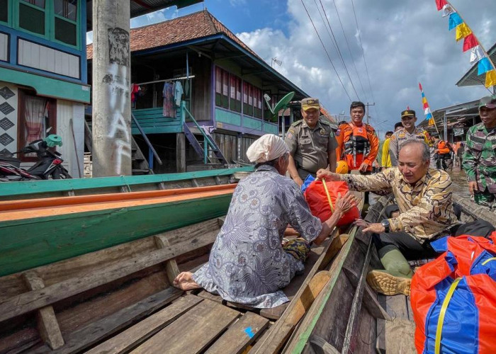 Pakai Perahu, Pj Bupati Muba Bagikan Sembako Bagi Warga Desa Rantau Kroya Terdampak Banjir