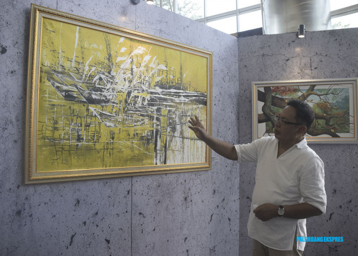 Pelukis M. Iqbal J. Permana menjelaskan lukisan dengan judul Dermaga Gudel dengan media gambar berukuran 150 x 100cm pada pameran KolaborArt 66 di Lobby Bank Sumsel Babel (BSB), Jakabaring, Rabu, 25 Oktober 2023. Foto: Alhadi Farid/Palpres.Com